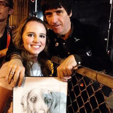 Photo of Artist Chelsea Smith with Guitarist Johnny Marr from the band The Smiths holding an original pet portrait of his pet dog that artist Chelsea Smith created for him.